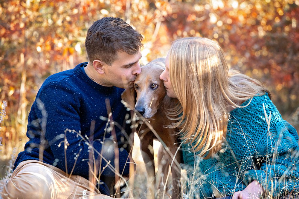 Couple kissing their hound dog